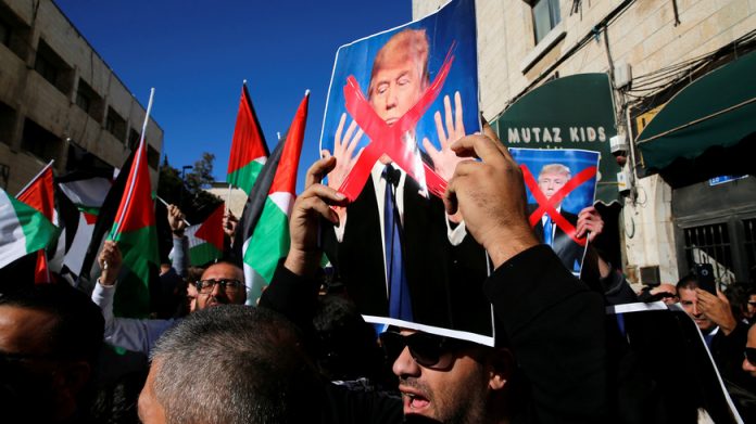 Palestinian protestors hold Palestinian flags and pictures of U.S. President Donald Trump during a demonstration in a street in east Jerusalem