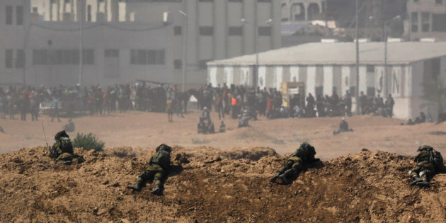 Smoke rises as Israeli soldiers are seen on the Israeli side of the border with the Gaza Strip