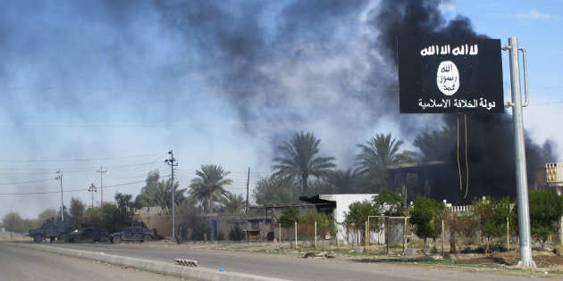 Smoke raises behind an Islamic State flag after Iraqi security forces and Shiite fighters took control of Saadiya from Islamist State militants