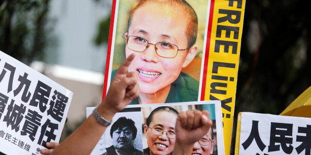 Protesters carrying photos of Chinese dissident demonstrate near a flag raising ceremony for China's National Day in Hong Kong