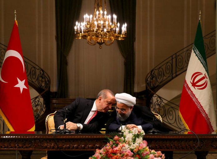 Turkish President Erdogan chats with Iranian President Rouhani during a joint news conference in Tehran