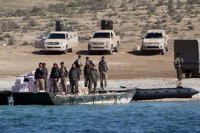 FILE PHOTO: Syrian Democratic Forces (SDF) fighters stand near food supplies on the bank of the Euphrates river, west of Raqqa