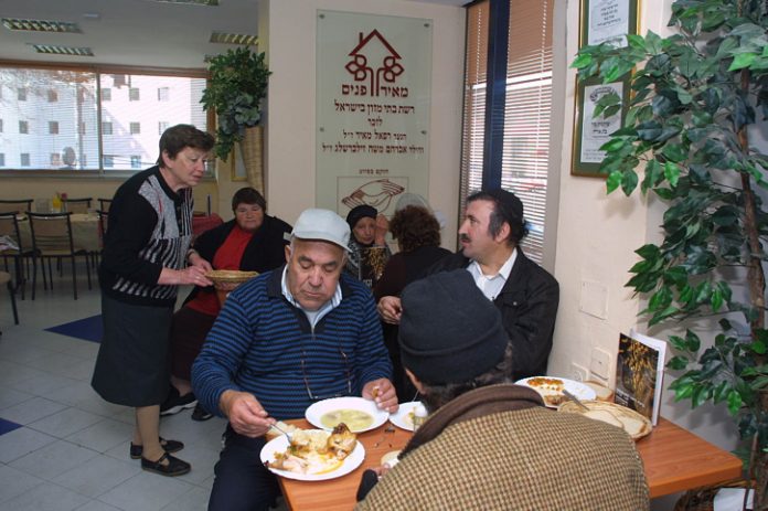Poor people in Jerusalem eat in a soup kitchen where they receive free meals