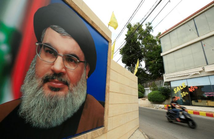 A man rides a motorbike past a picture of Lebanon's Hezbollah leader Sayyed Hassan Nasrallah, near Sidon