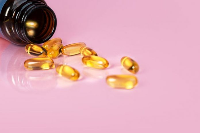Vitamin D bottle with capsules on yellow background. Omega 3.