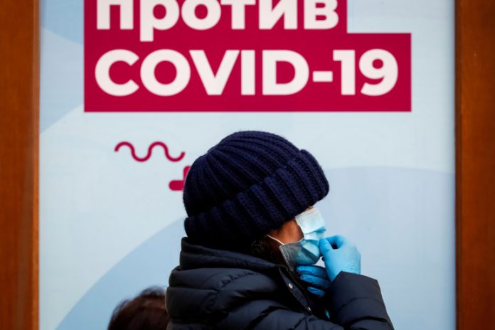 FILE PHOTO: A woman walks past a sign outside a vaccination centre in the State Department Store, GUM, in Moscow