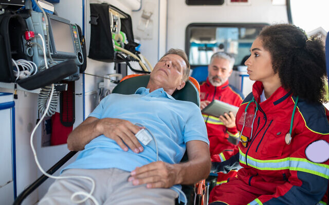 Female paramedic monitoring the patient heart rate using medical equipment